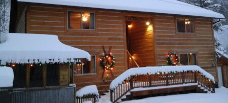 Winter snow and Christmas wreaths with lights on log sided condos.