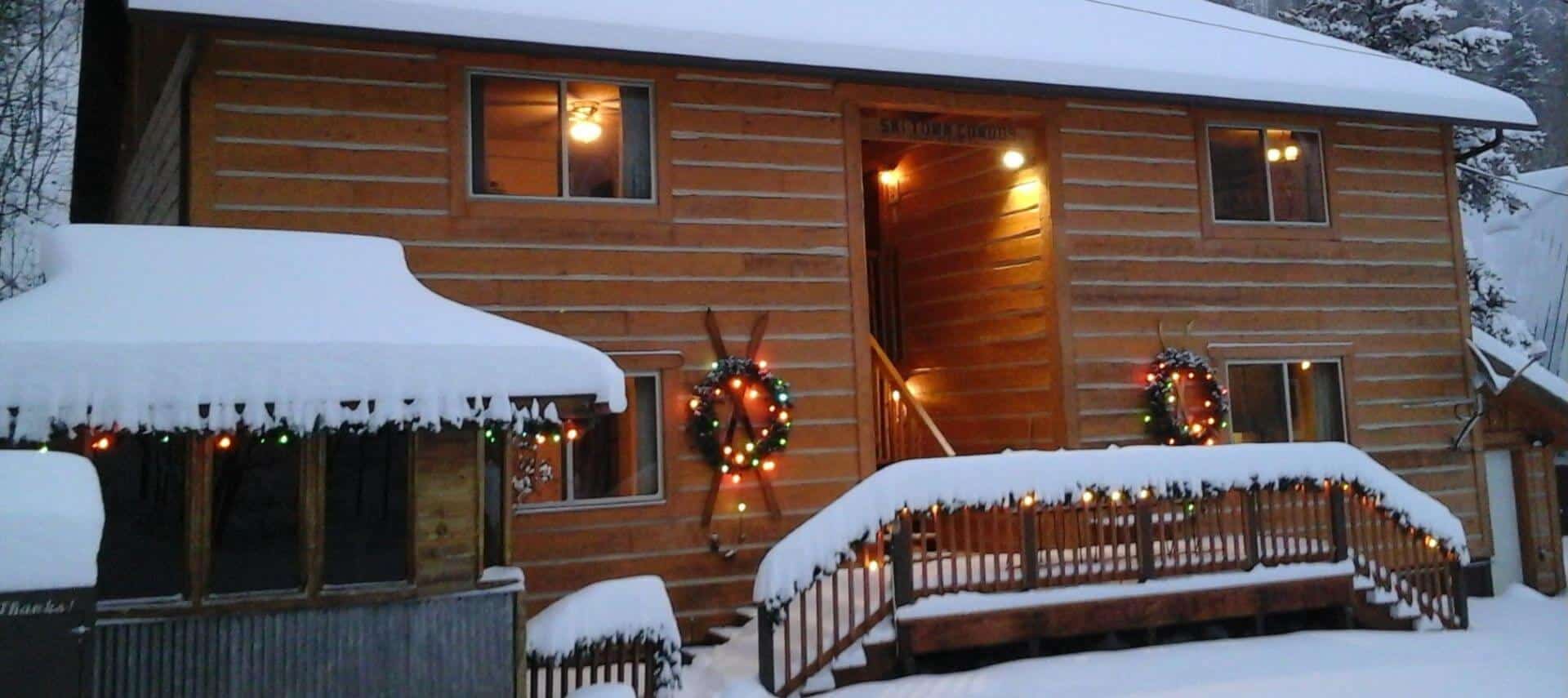 Winter snow and Christmas wreaths with lights on log sided condos.