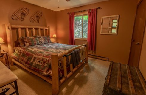 Guest bedroom with a queen size log bed with trunk.