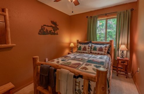 Guest bedroom with log bed, and ceiling fan.