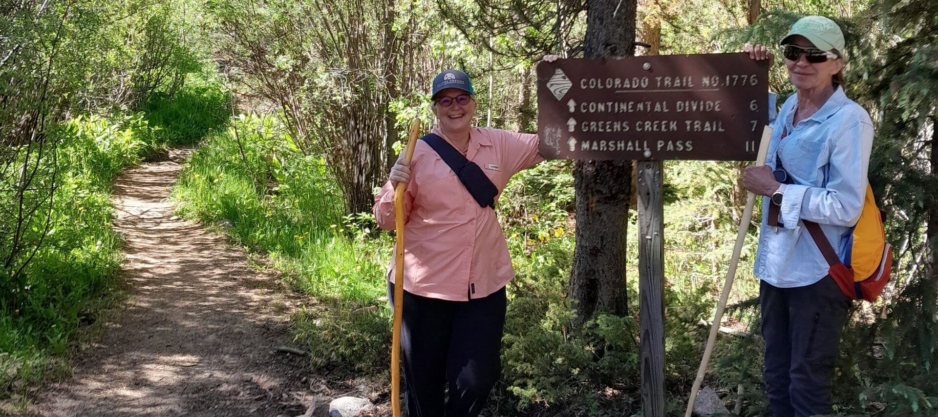 Two ladies with hiking sticks standing next to the sign.