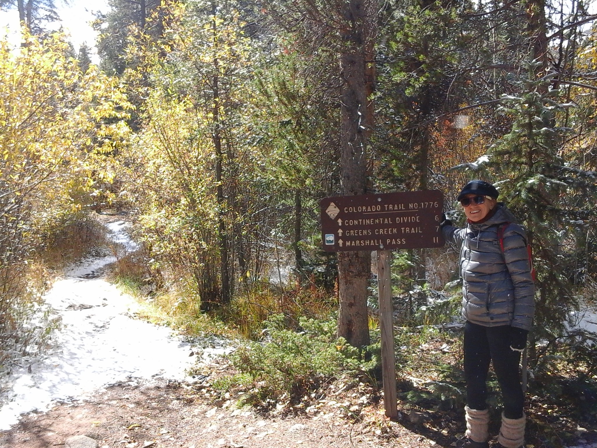 A lady hiking on a fall day in a winter coat, gloves, hat, and boots.