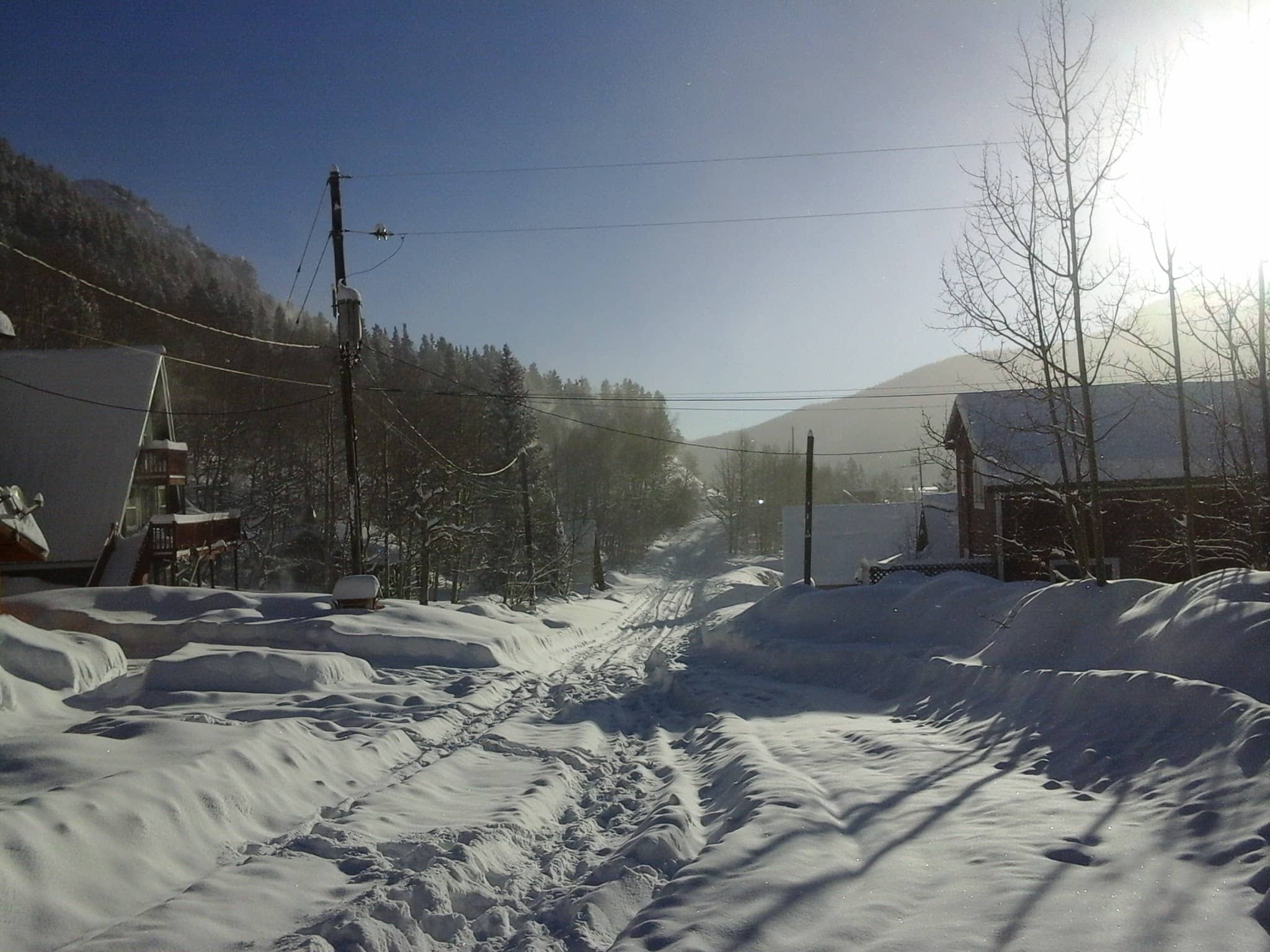 Beautiful sunny morning with 40 inches of fresh snow covering a road with cabins on each side.