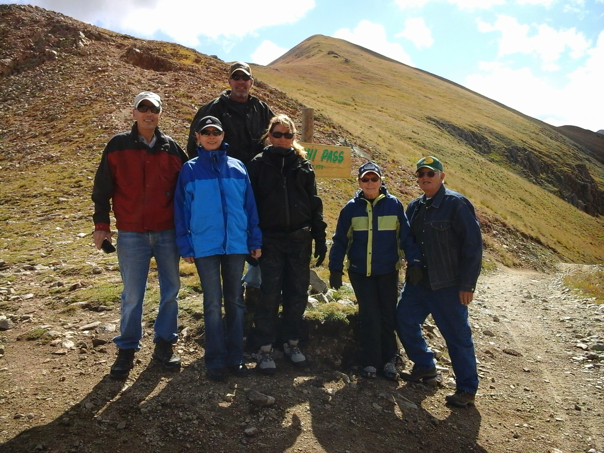 Seven people standing on the mountain road with fall colors all around.