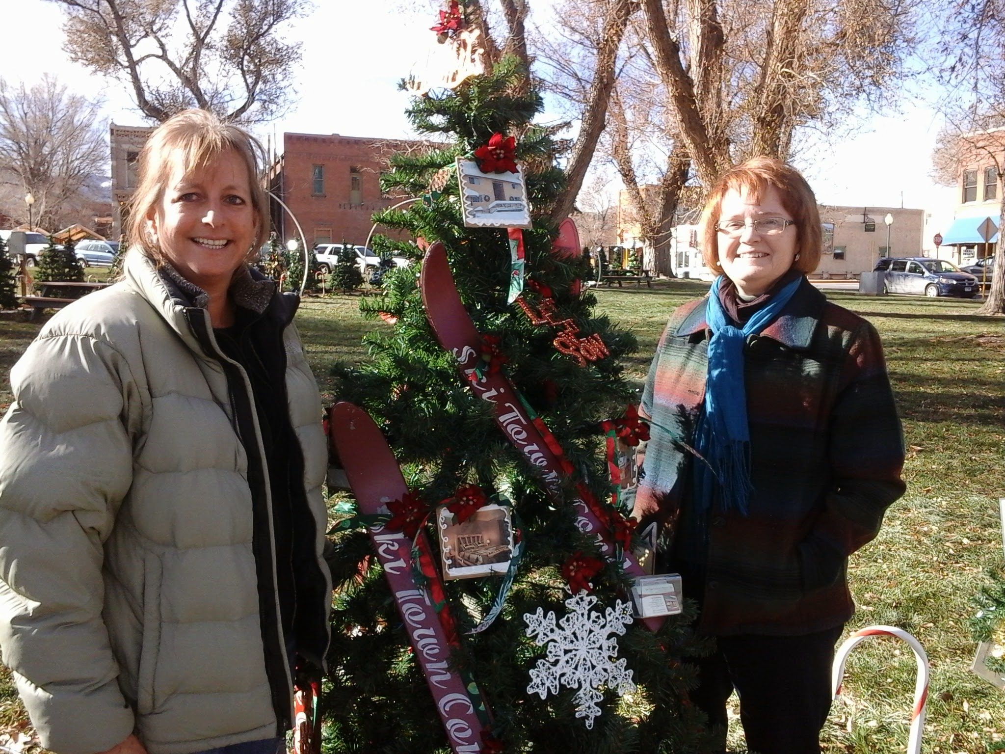 Exterior photo of a Christmas decorated with skis, two women smiling next to tree.