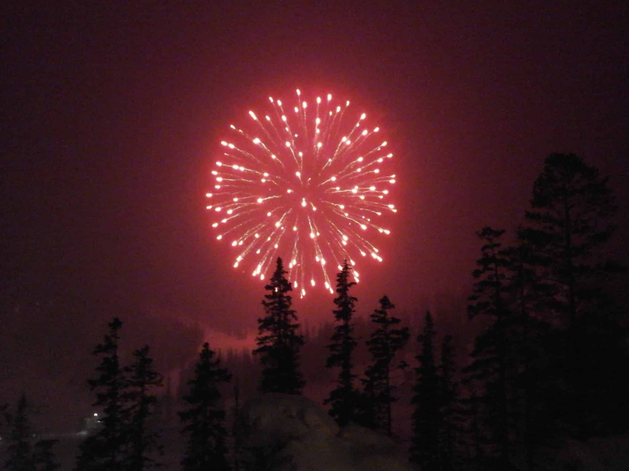 Evening winter scene with a huge red firework shinning in the night at ski area.