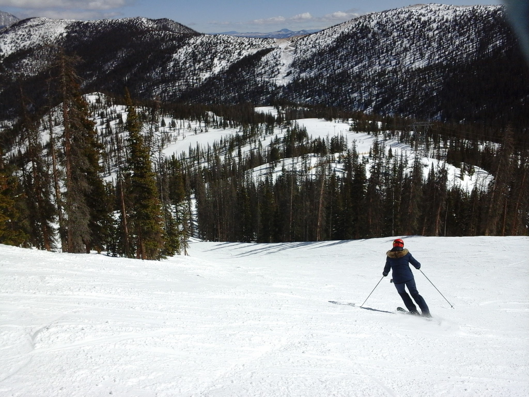 Person skiing down a ski run on a spring day.