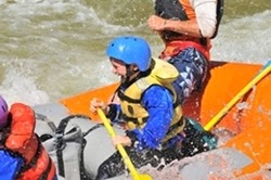 Young boy rafting in the river with family.