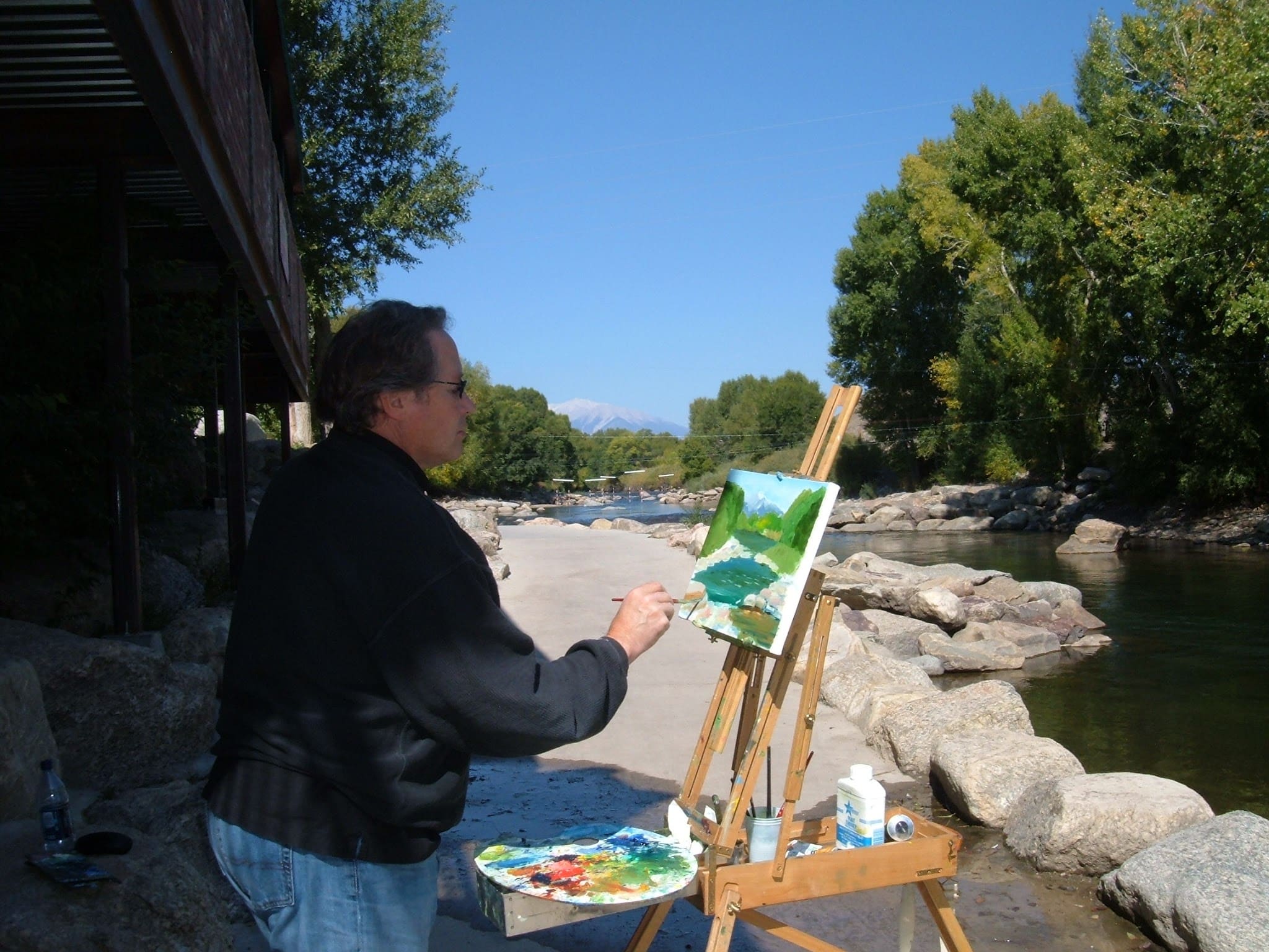 An artist paint outside along the river bank.