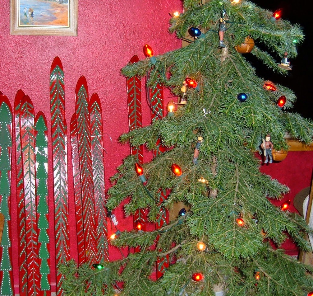Painted skis with Christmas trees standing up on the wall.