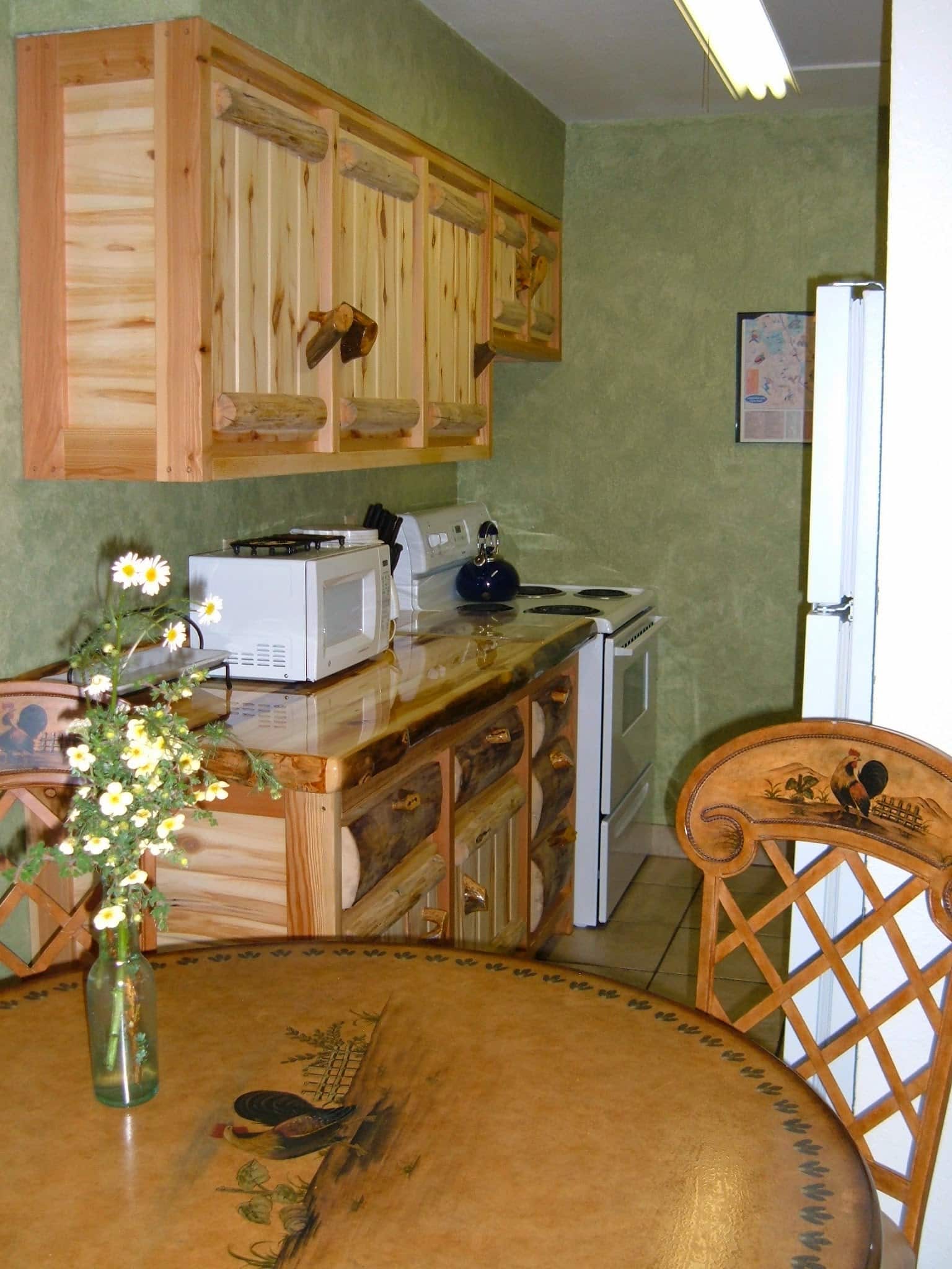Kitchen with beautiful log cabinets, tile floors, and faux green walls.  Dinning table with faux painting of a rooster
