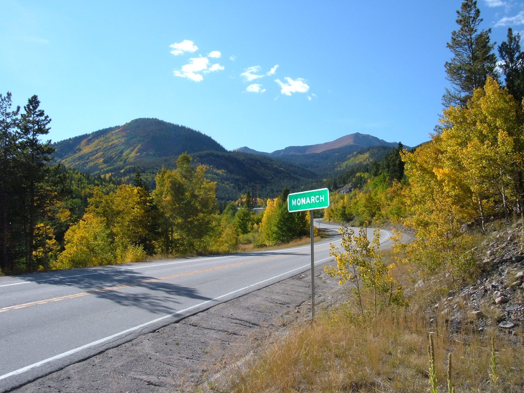 Highway sign along a mountain pass with fall colors on the Aspen trees.