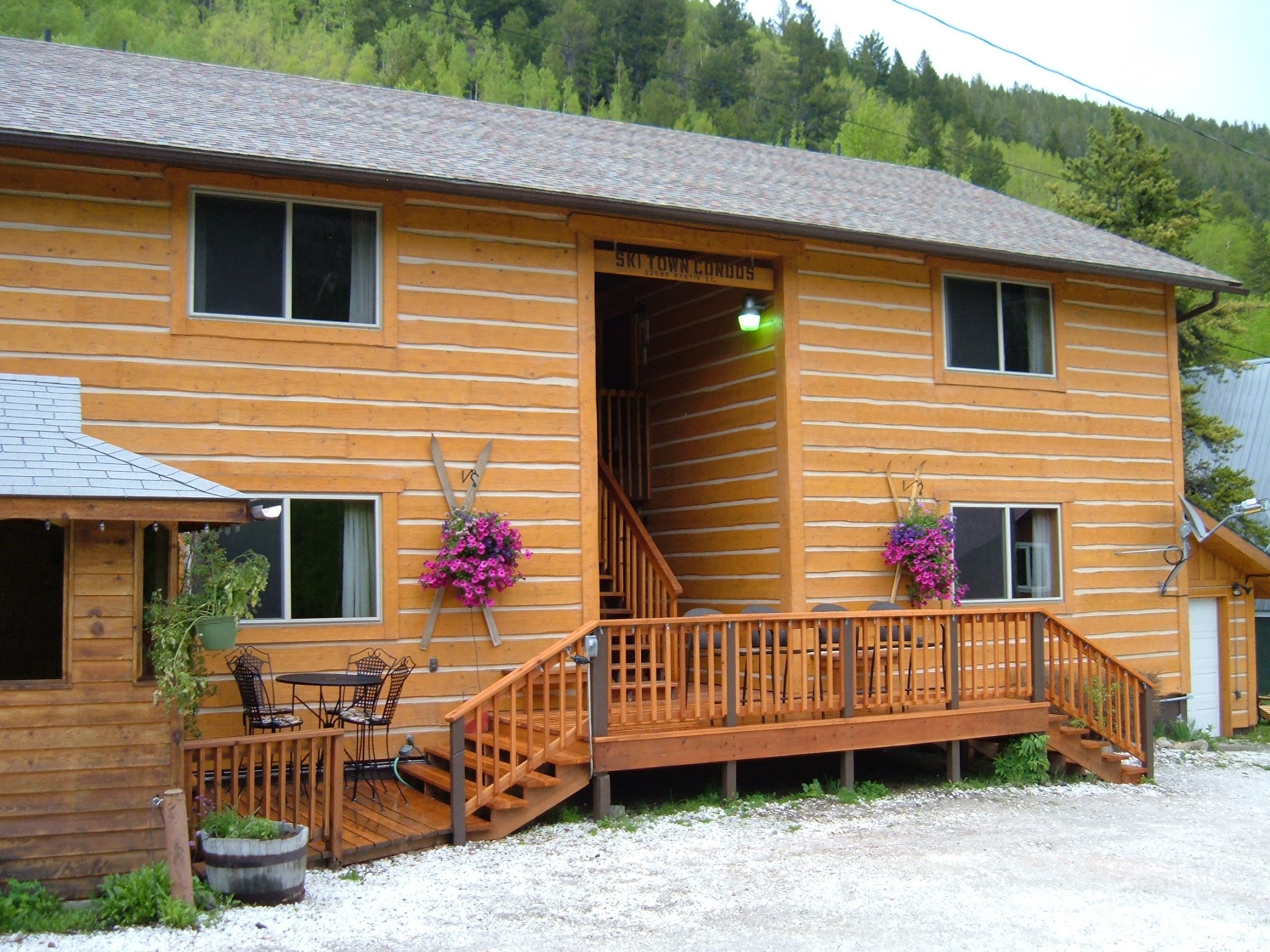 Log sided condos, autum gold, with 2 large hanging baskets of pink flowing flowers.