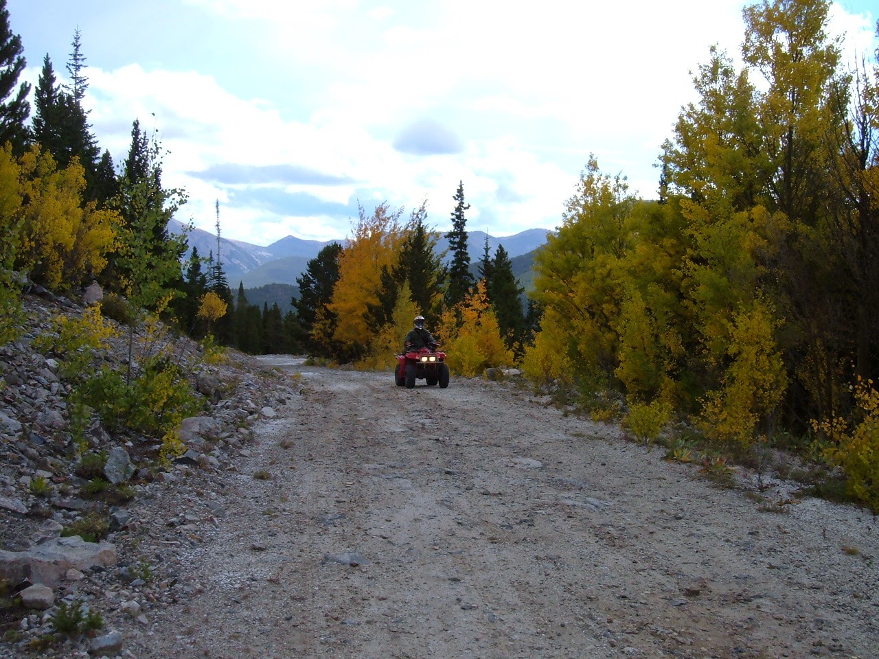 ATV riding along a mountain road with fall colors all around.