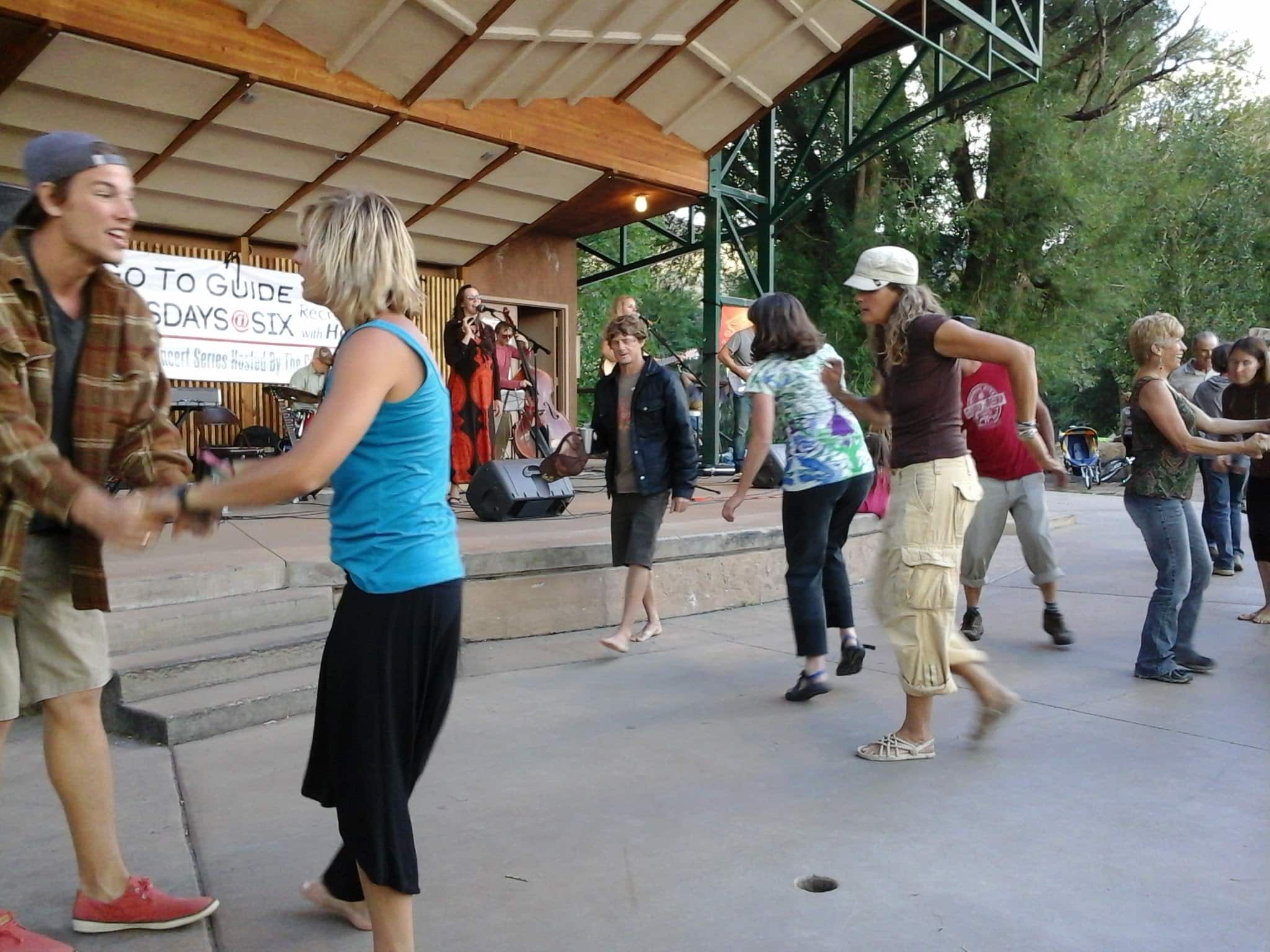 People dancing to the live music along the river park.