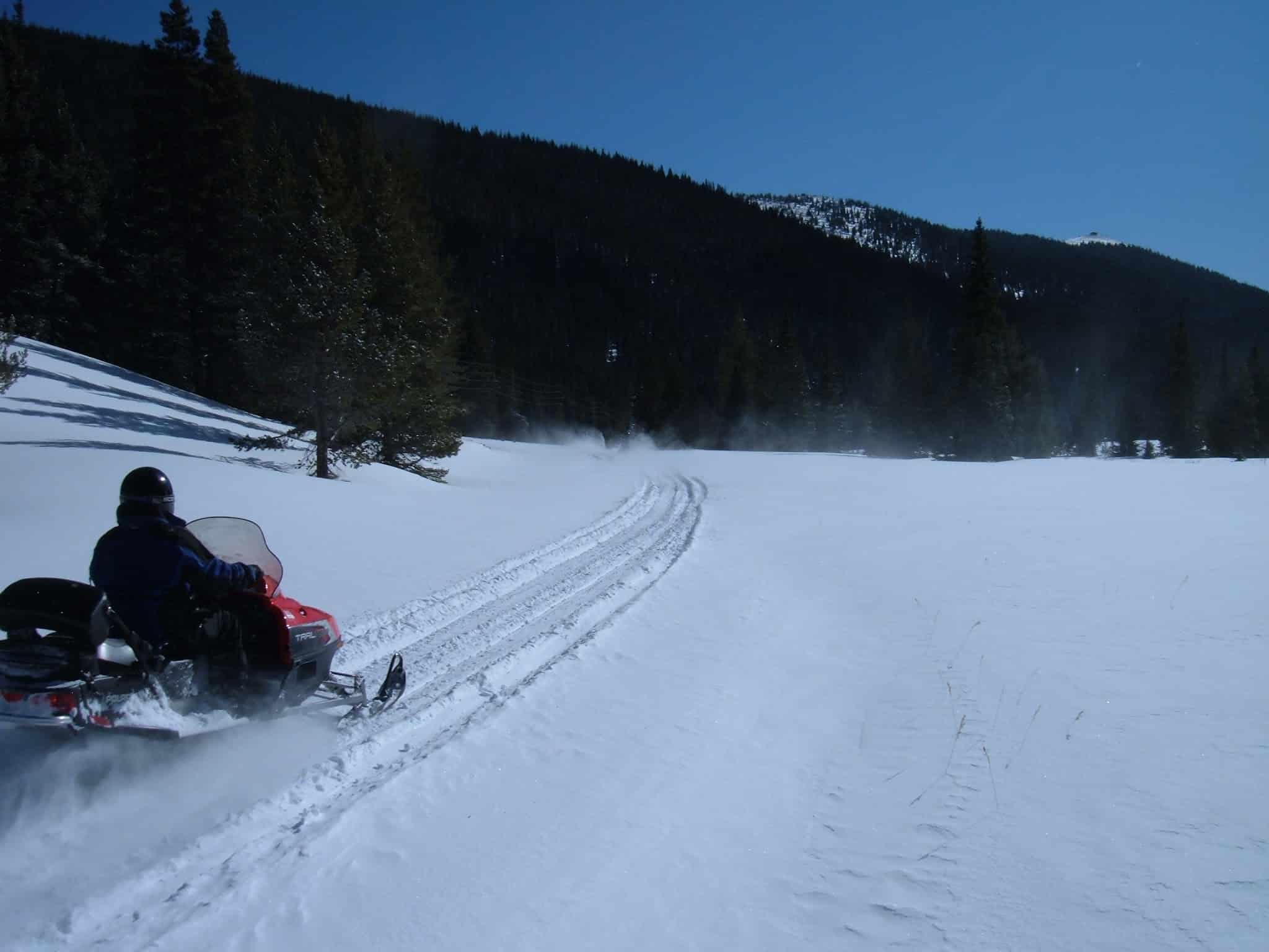 Snowmobiling on a packed trail in the open field.
