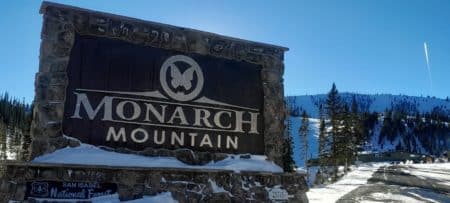 Monarch Mountain stone entrance sign to ski area, blue sky and snow on the ski trails.