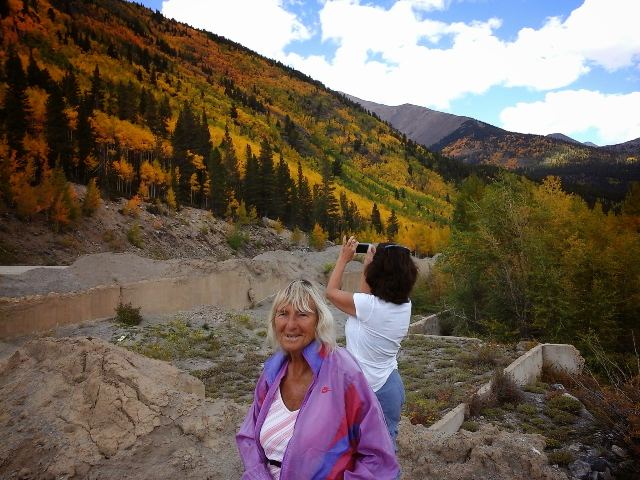 Two ladies taking photos of the fall colors in the mountains of Aspen Trees.
