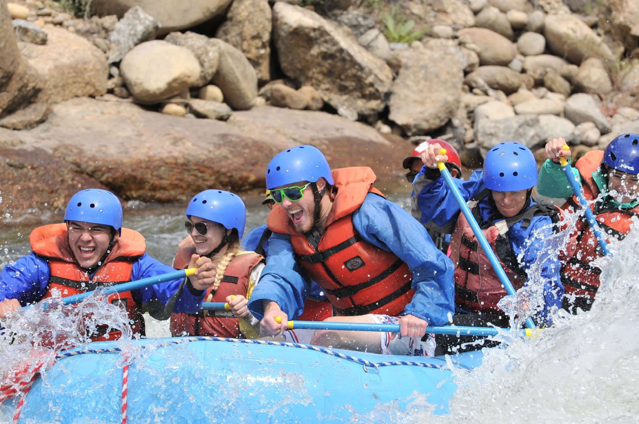 Exterior rafting photo with 7 rafters paddeling in the river.