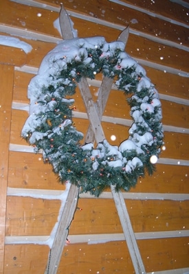 Exterior winter scene with antique skis and Christmas lights on wreath.