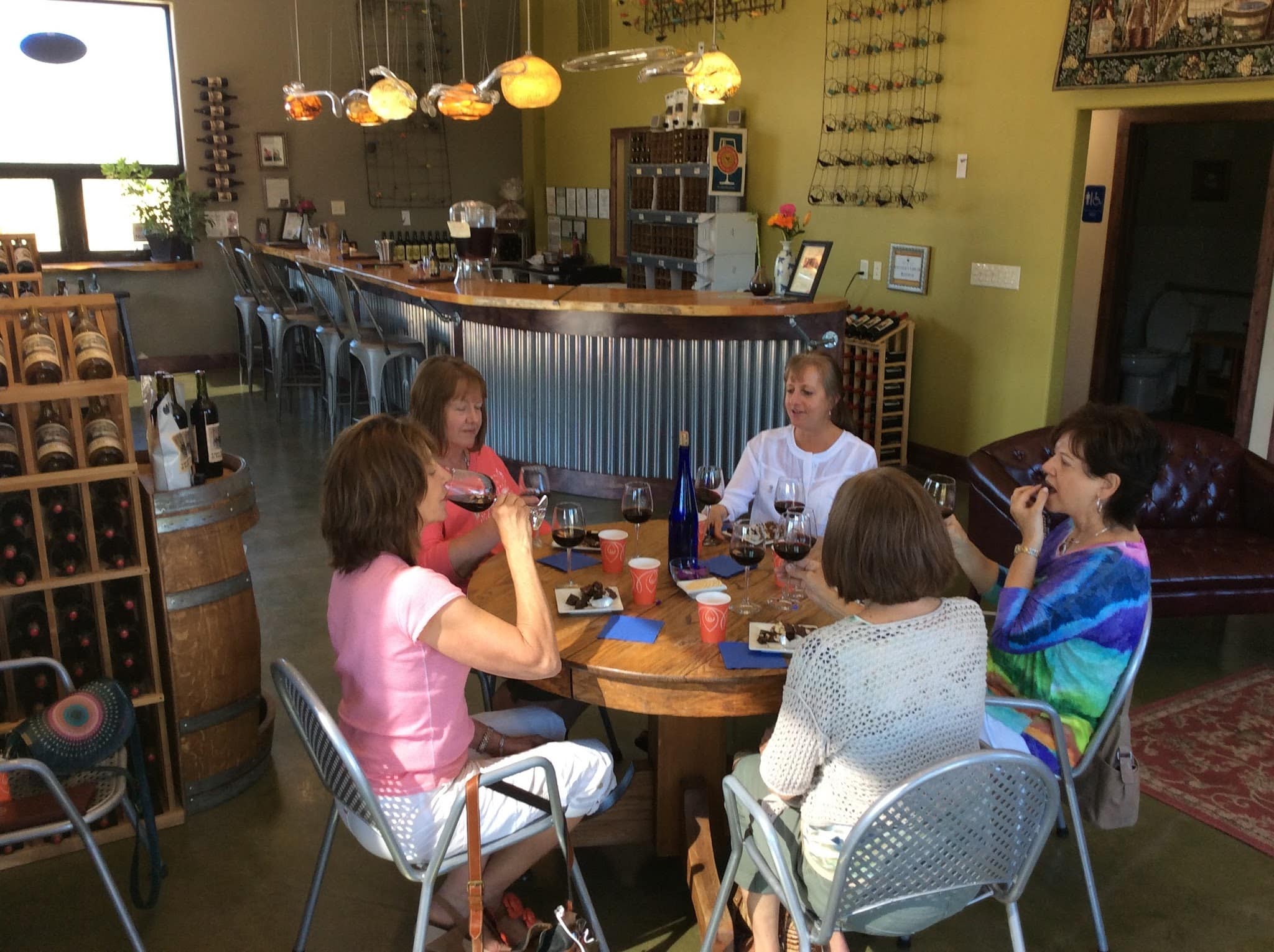 Five ladies wine tasting around a round table.