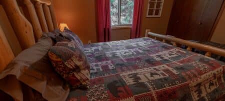 Log bed with a lodge quilt, brown walls.