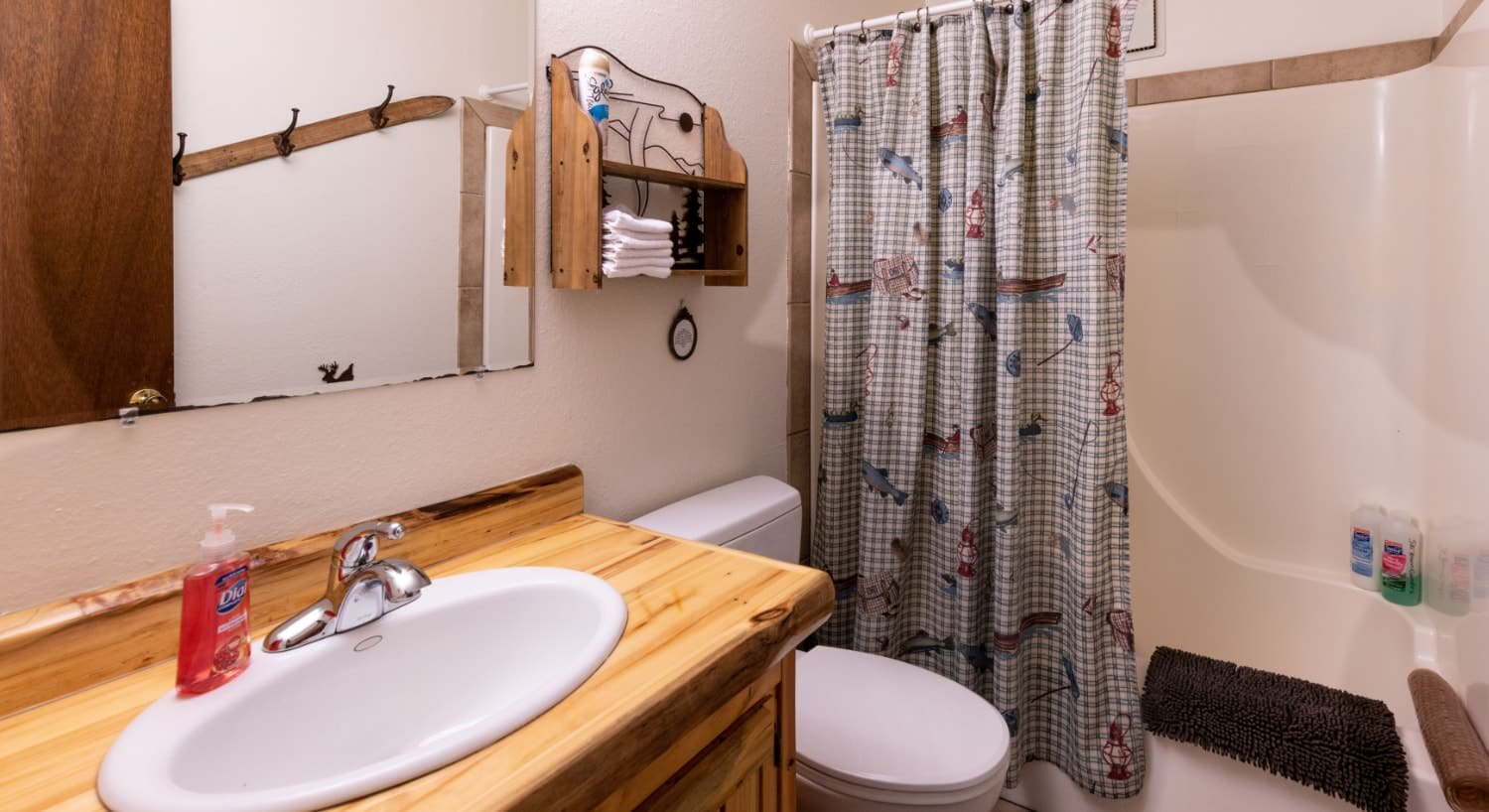 Bathroom with white walls, wooden vanity, white sink, white stand up shower, and large mirror