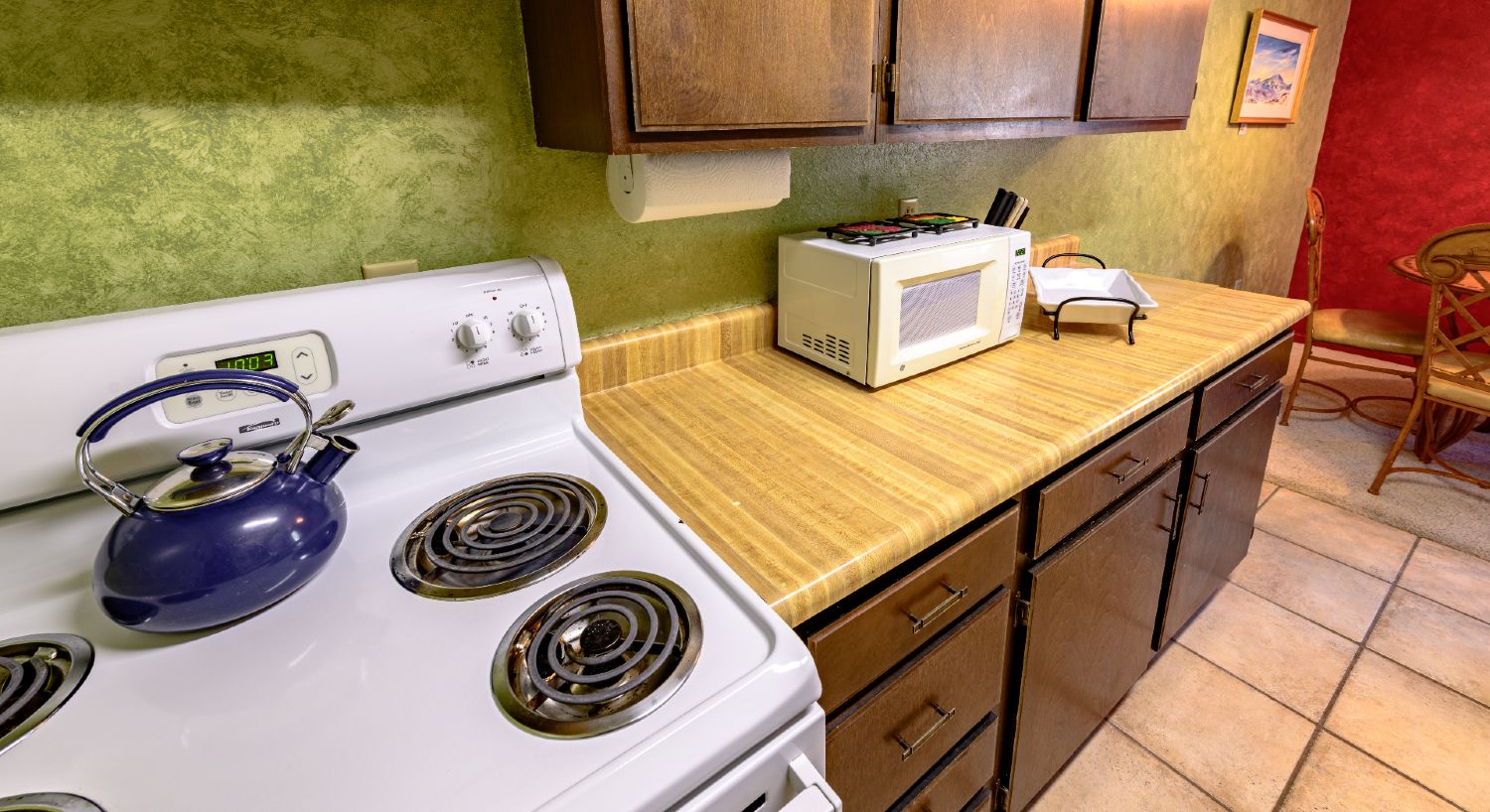 Vintage kitchen cabinets, four burner stove and oven, tile floors. 