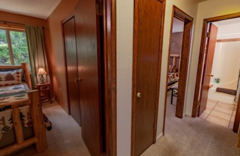 Hallway with cream walls, carpeting, and views into two bedrooms and a bathroom
