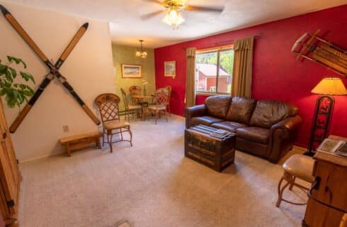 Lodge view living room with antique skis on wall, leather sofa, antique trunk, and dining table.