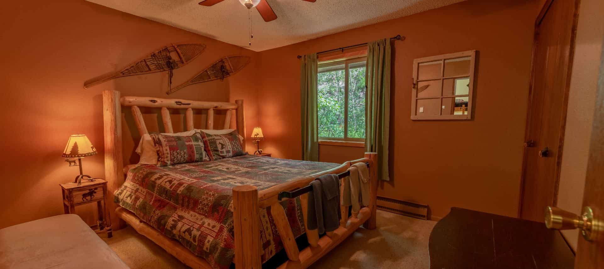 Bedroom with brown walls, carpeting, wooden log bed, homemade quilt, and wooden nightstands