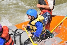 Young child having a huge smile rafting with his family.