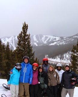 A snowmobile tour of eight guests on a snowing day with the ski area in the distance.