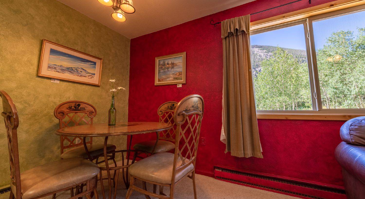 Round dining table with 4 chairs and two  paintings hanging on the walls.