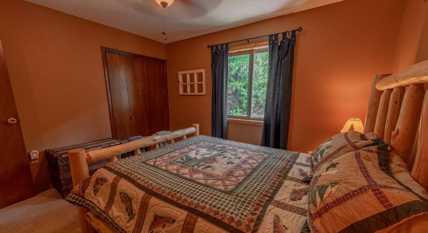 Guest bedroom with a queen size log bed with a charming quilt with fish; brown walls.