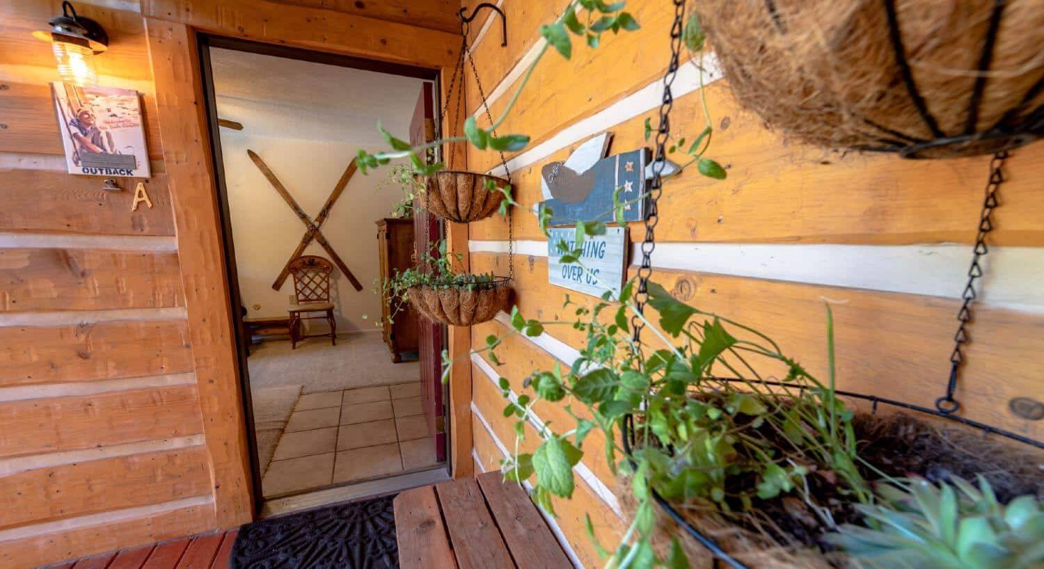 Entrance to condo with log siding, hanging plants, looking into the living room.