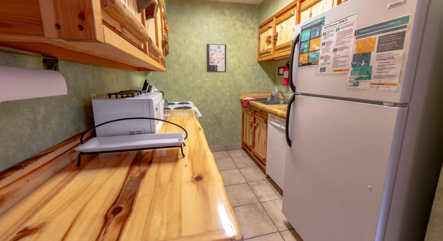 Kitchen with green walls, light colored flooring, wooden counters and cabinets, and white appliances