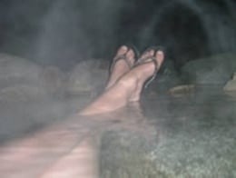 Outdoor hot springs with crossed feet resting.