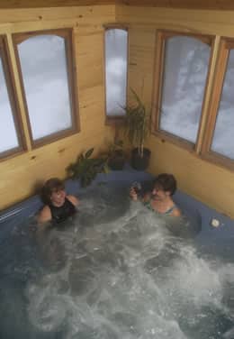 Two ladies sitting in an enclosed hot tub with windows.